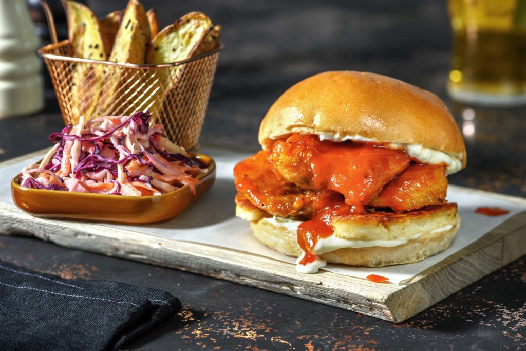 The Hot Chick is a zingy sensation of sunshine flavours and tThe Hot Chick - Crispy Chicken & Halloumi Burger, Hot Honey, Sesame Wedges and Lime Mayo Slaw.