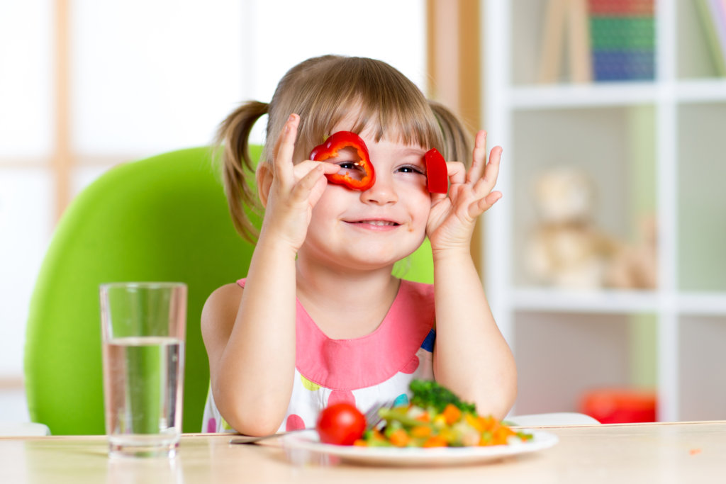 Vegan Vorteile: Kleines Mädchen spielt mit Gemüse